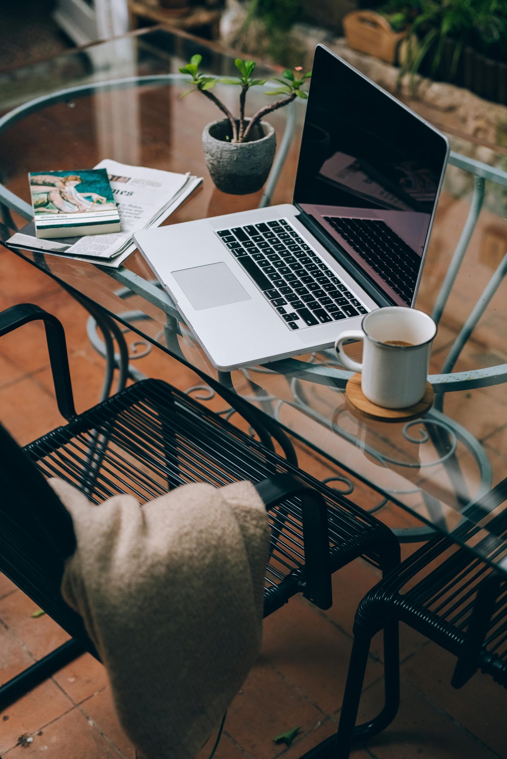 A cozy home office setup featuring a laptop, coffee mug, and decor on a glass table.
